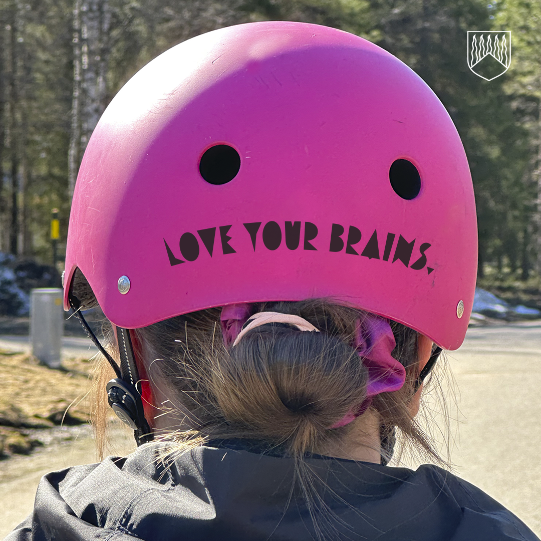 Kuvassa henkilö pinkki pyöräilykypärä päässään. Kypärässä teksti Love your brains.