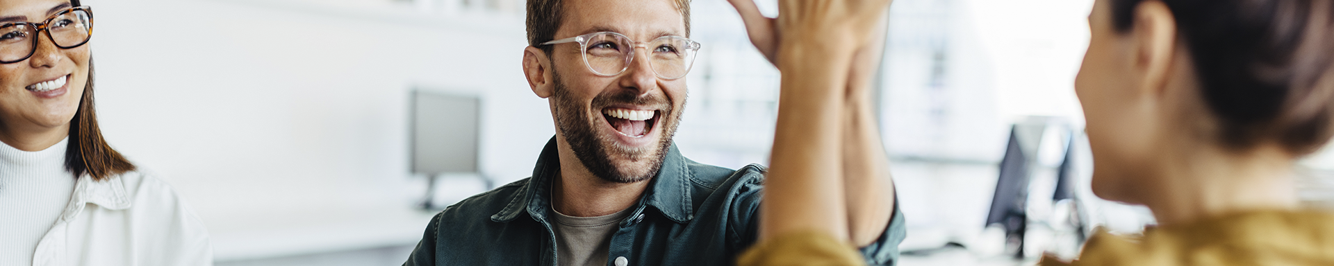 Iloiset ihmiset lyövät käsiä yhteen toimistossa.