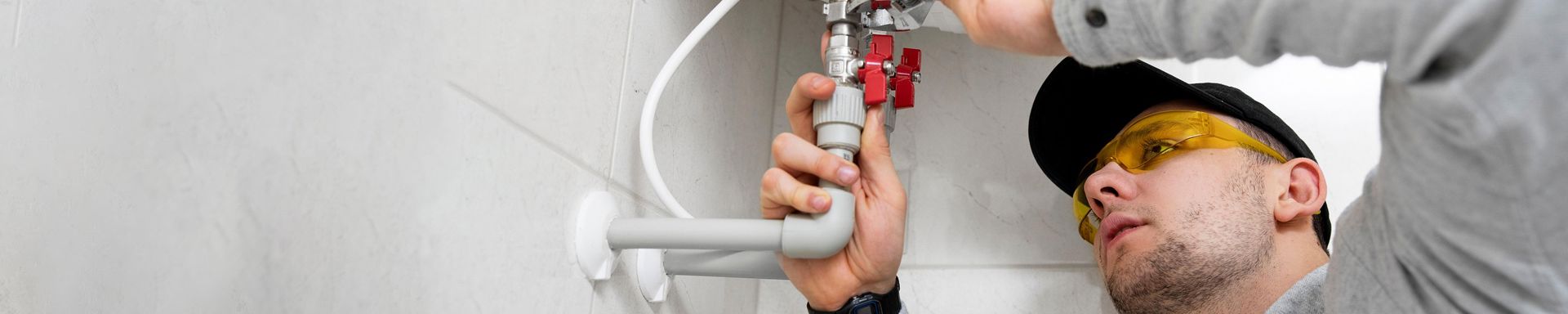 Huoltomies korjaa keittiöhanan putkistoa.