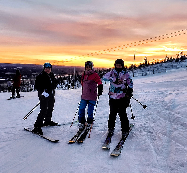 Kuvassa kolme iloista laskettelijaa Ylläksellä laskettelu rinteessä.