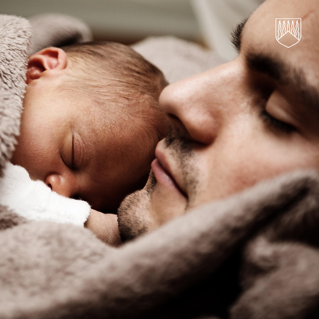 Kuvassa vauva makaa pehmeän, harmaanruskean peiton alla. Vauvan pää ja osa vartalosta näkyvät peiton alta, ja ympäristö vaikuttaa olevan sisätila, esimerkiksi sänky tai pinnasänky. Peitto on pörröinen ja luo lämpimän, kodikkaan tunnelman.