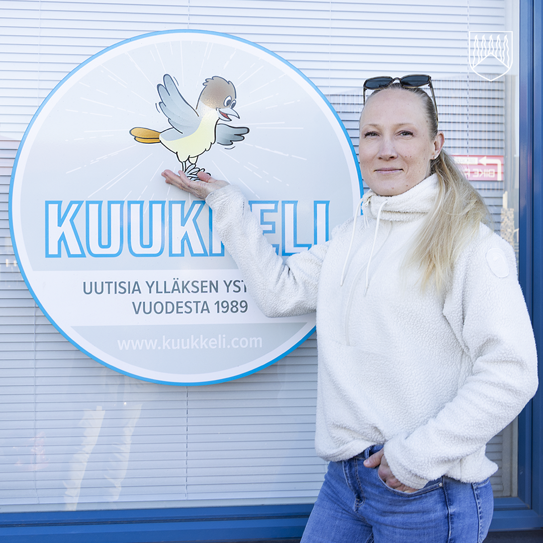 Vuoden 2026 yrittäjäpalkinnon saanut Satu Renko Kuukkeli-lehden kyltin vieressä Äkäslompolossa.