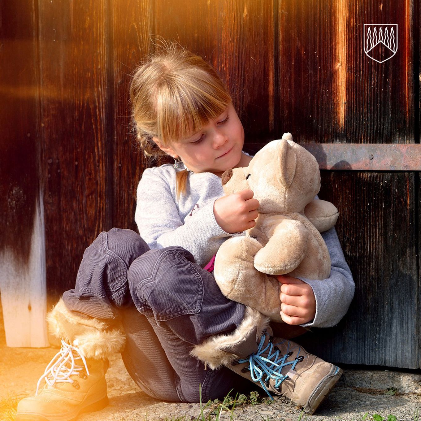 Lapsi istuu sylissään nallekarhu pehmolelu silittäen nallen poskea.